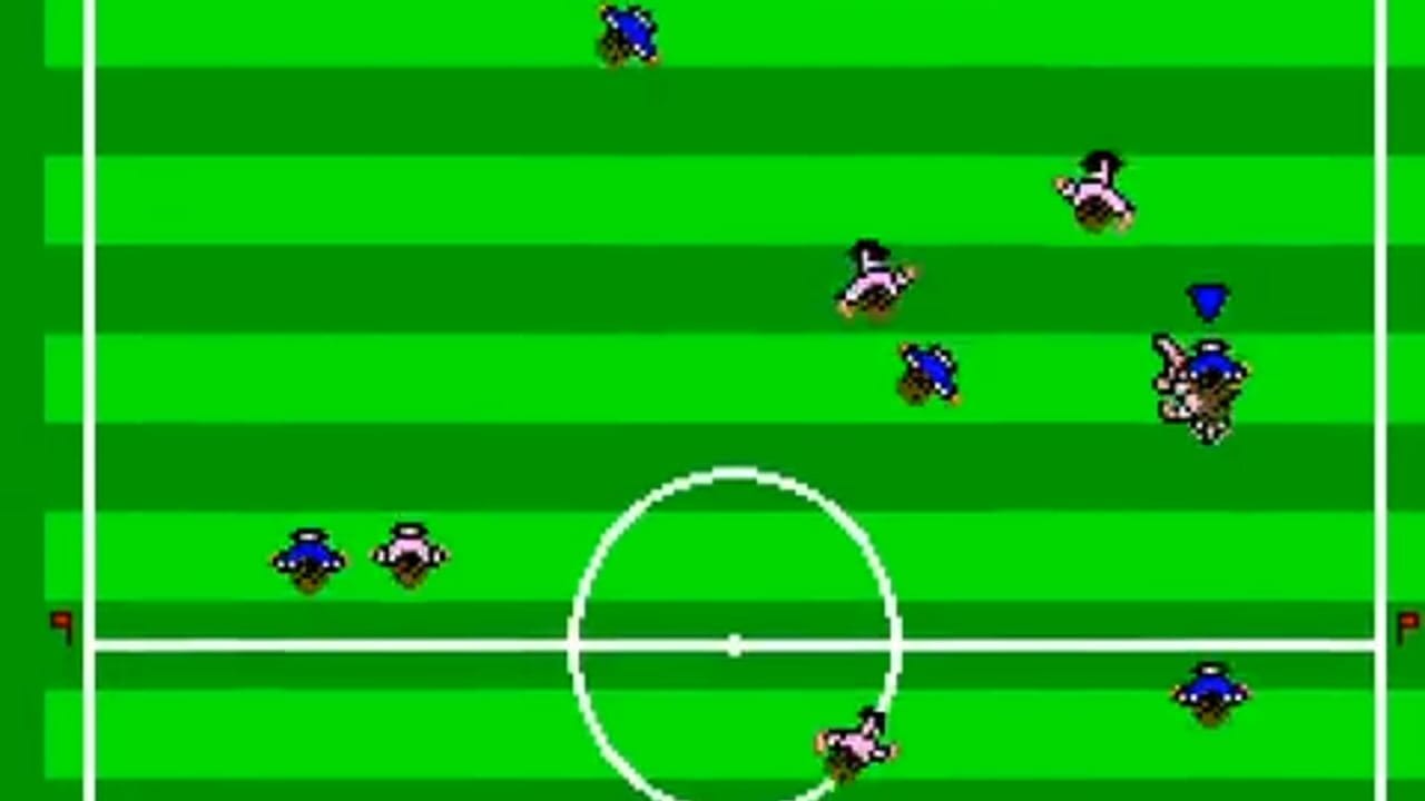 A soccer field with alternating light and dark green horizontal stripes is divided by white lines marking the center circle and halfway line. Ten pixelated player sprites in two teams—one wearing blue jerseys, the other in white and black striped jerseys—are positioned across the field at various locations. A blue ball sprite floats near the top center. The field boundaries are marked by white sidelines and goal lines on the left and right edges.