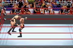 A wrestler in brown and tan attire performs in a WWF-branded wrestling ring with red-and-white rope borders. The overhead scoreboard displays match information and wrestler names at the top of the screen. A crowd of spectators fills the background behind the ring barriers. The graphics use sprite-based character models and a flat perspective typical of GBA-era sports games, with a low resolution rendering of the wrestling arena environment.