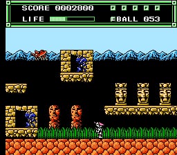 A side-scrolling action scene displays a player character in red and blue standing on a brown platform, with two identical red enemies nearby. Snow-capped mountains form a parallax background layer. A large golden structure with multiple cube blocks rises in the center-right, while smaller golden platforms and blocks scatter the lower terrain. Green grass forms the ground level. The HUD shows score 0602800, a green life bar, and ball count 053 in the upper-left corner with a black-bordered white band.