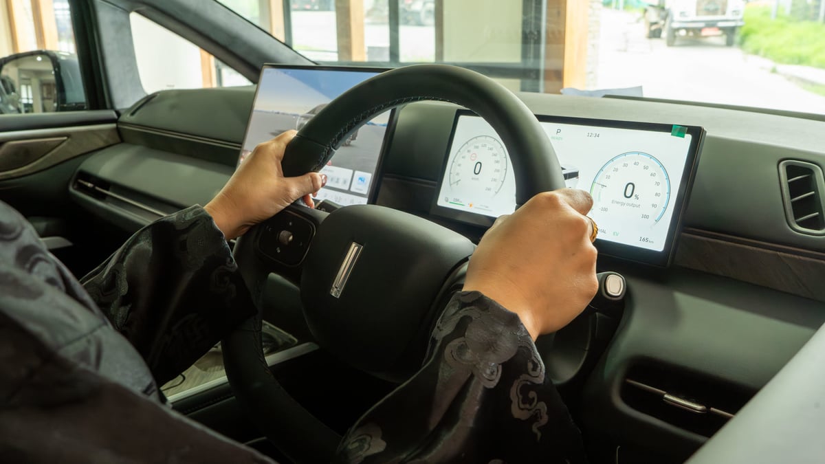 Hands on the WEY G9 steering wheel with the twin displays lit ahead