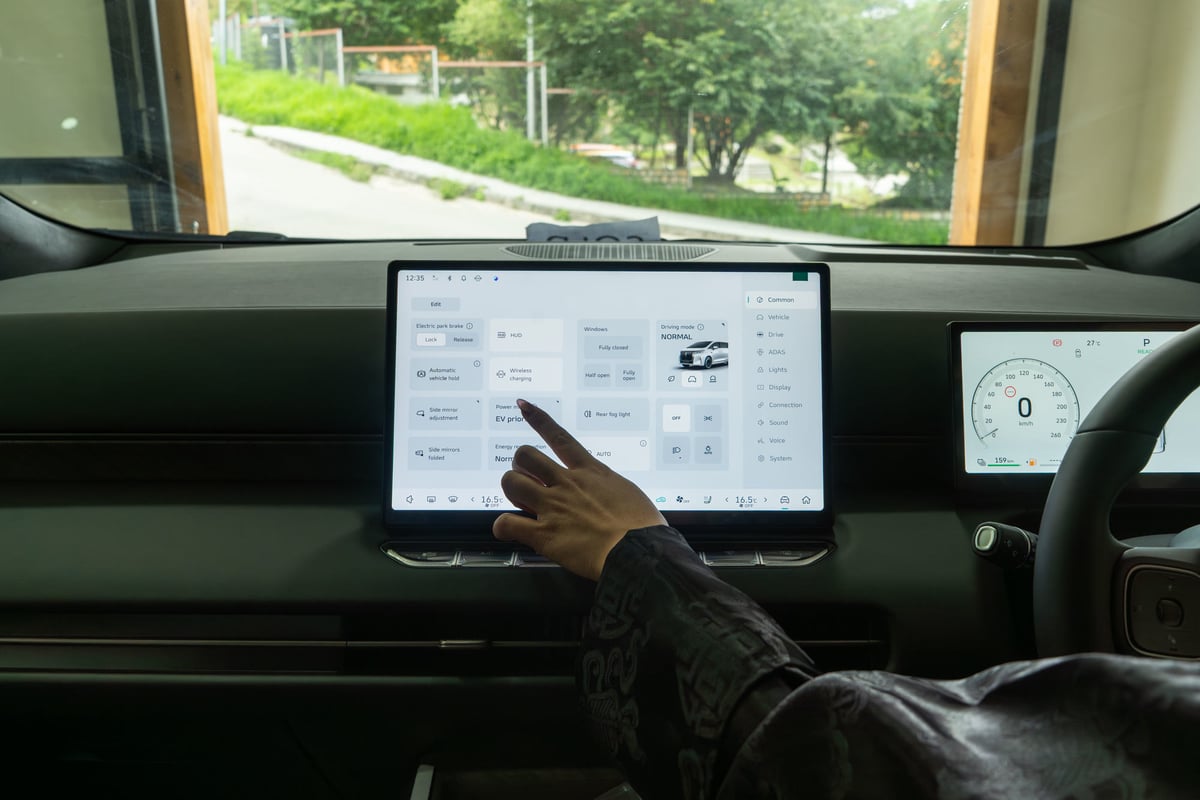 A hand operating the WEY G9 centre touchscreen from the driver seat
