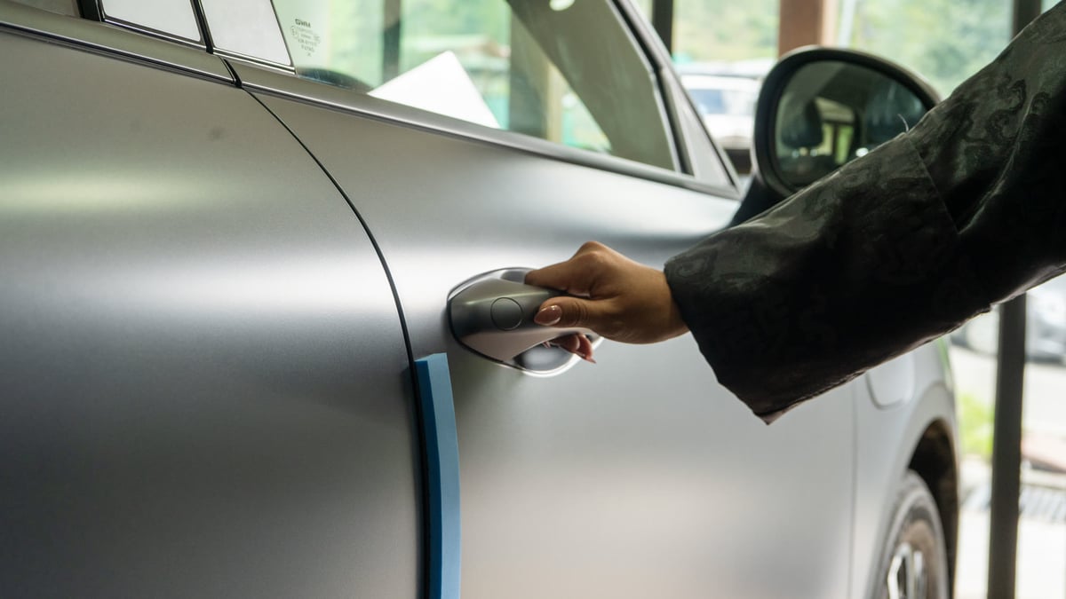 A hand on the door handle of a matte silver ORA 5