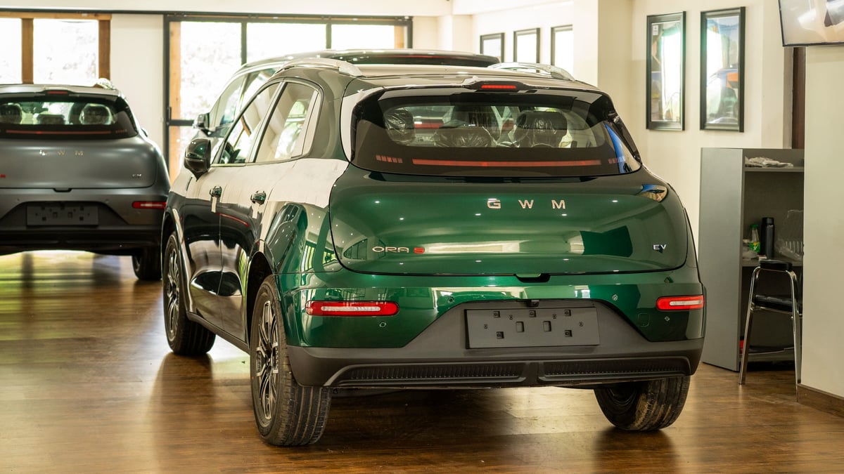 Green ORA 5 EV from the rear three-quarter inside the showroom