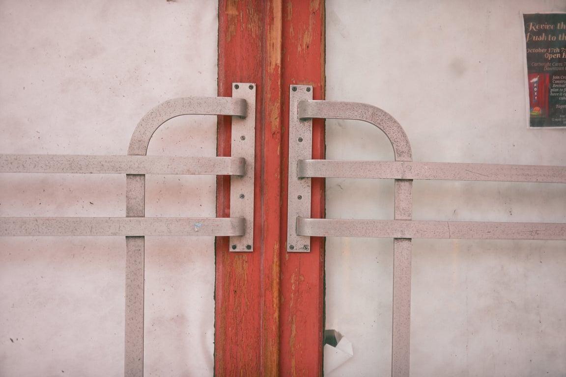 Weathered red double doors at the Roxy Theatre with a restoration campaign poster beside them.