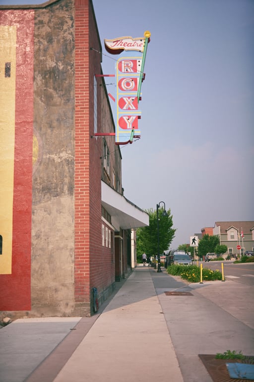 The vertical Roxy Theatre sign mounted on a brick building above a quiet Coleman sidewalk.