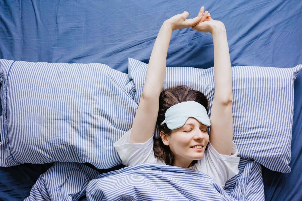 A young woman awakens in bed, feeling refreshed after a peaceful night’s sleep.