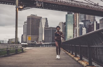 A full-length shot of a woman sprinting swiftly against a backdrop of a city skyline