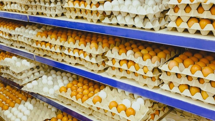 Cardboard trays with chicken eggs on shelves at supermarket