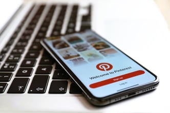 Close-up of an iPhone showcasing the Pinterest app alongside a MacBook laptop