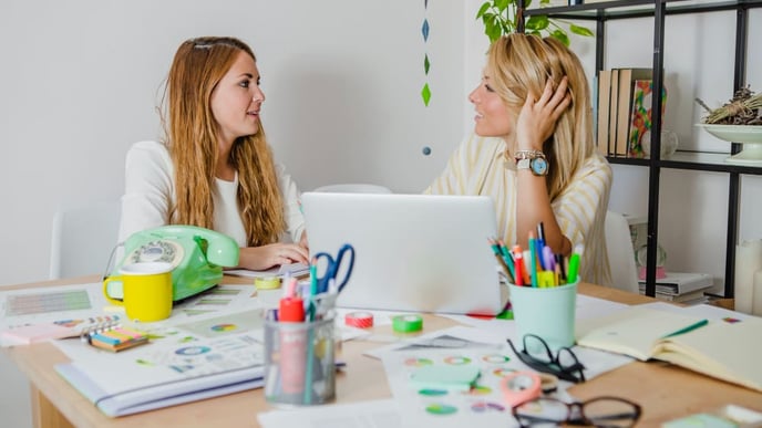 Two women collaborating and exchanging ideas on their projects