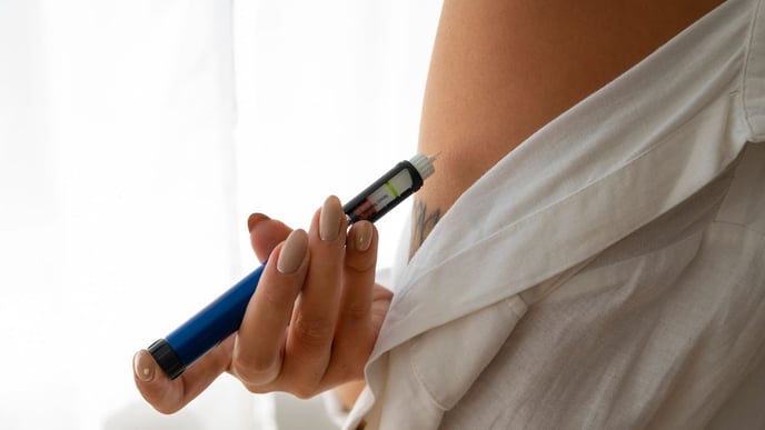 A woman independently administering weight loss medication, such as Ozempic, from a sideways perspective