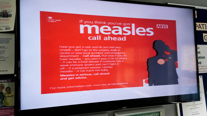 A sign warning people about measles in a NHS doctors surgery clinic