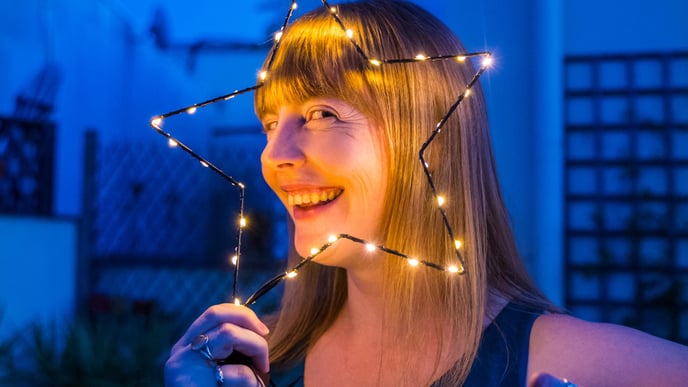 Close-up portrait of smiling woman holding illuminated star shape