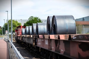 Large rolls of sheet metal lying on a freight wagon pulled by locomotives