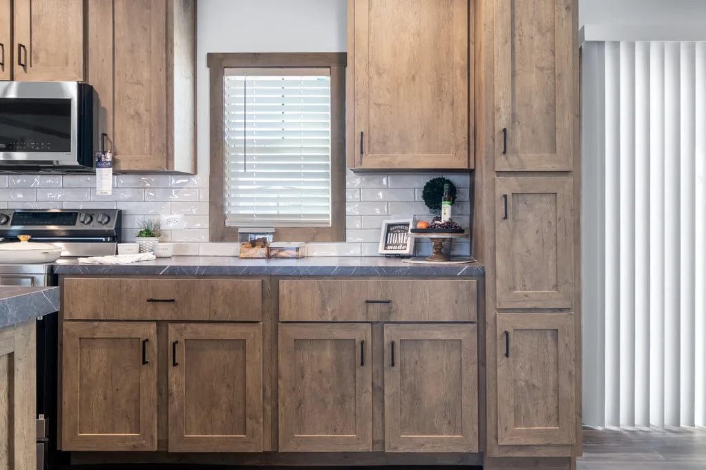 Wood kitchen cabinets and glossy subway tile in the Isabella Elite manufactured home