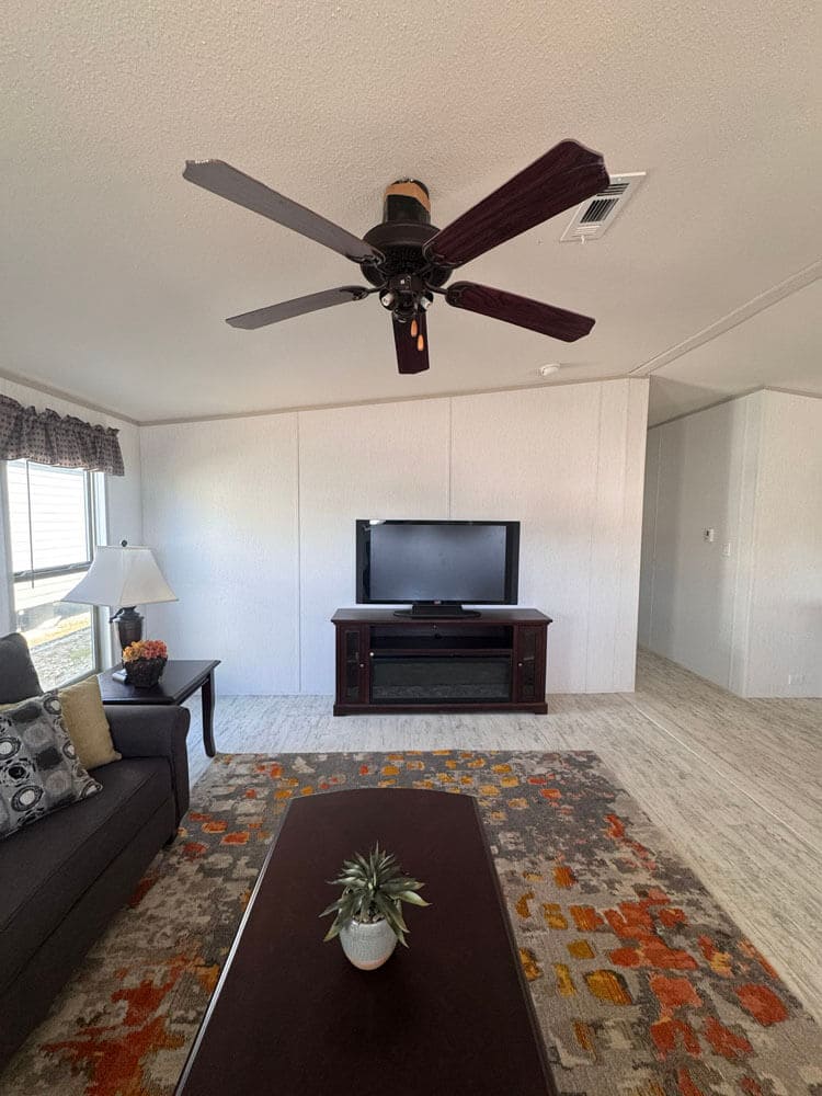 Living room with ceiling fan and entertainment area in The Lucia 3 bedroom doublewide