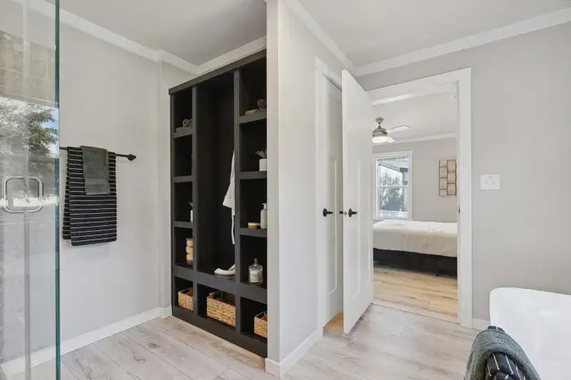 Primary bathroom with built-in linen storage and access to the bedroom in The Carol