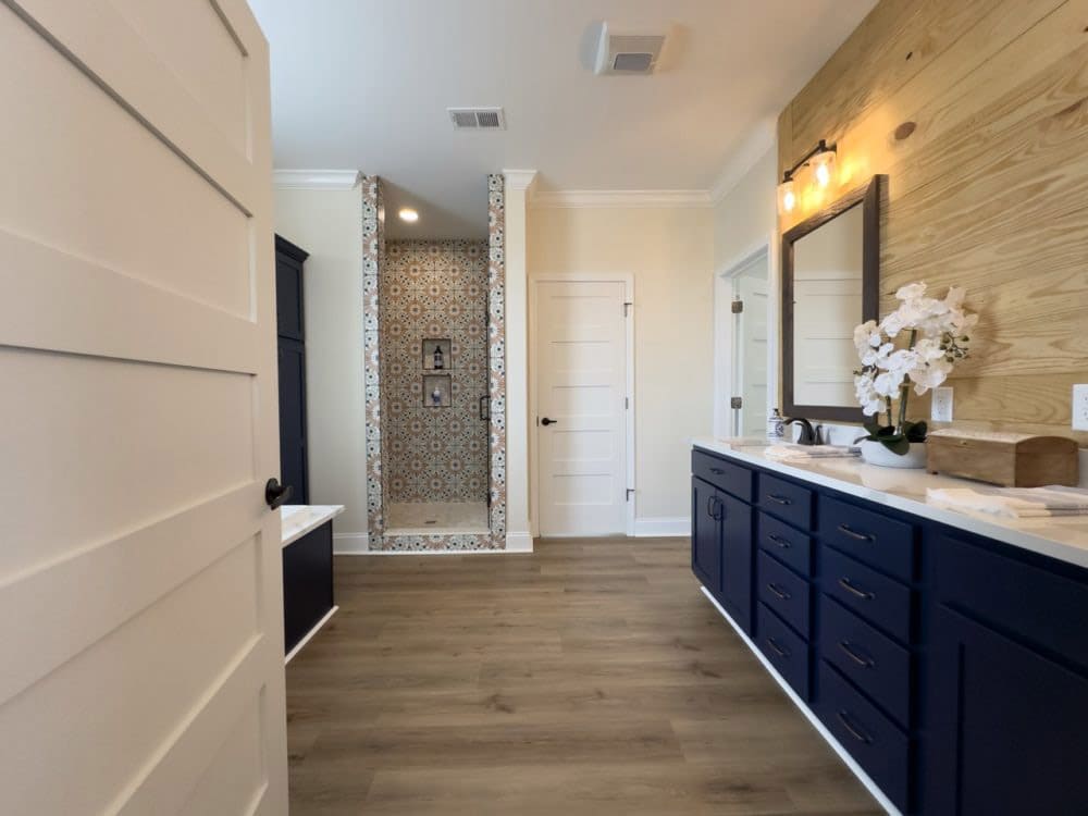Primary bathroom with patterned tile shower and navy vanity in The Riverwalk