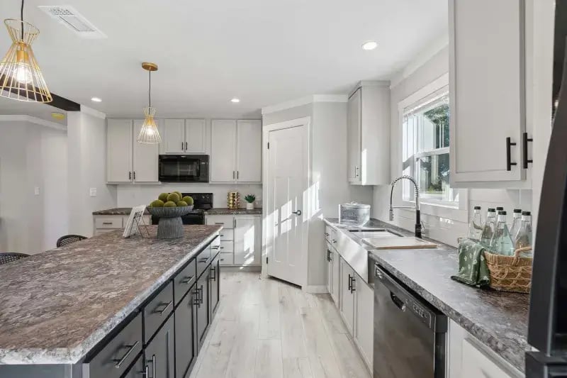 Kitchen workspace with large island, farmhouse sink and dishwasher in The Carol home