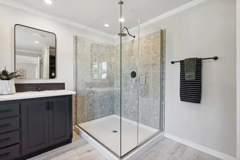 Glass-enclosed primary bathroom shower in The Carol 4-bedroom Champion Homes model