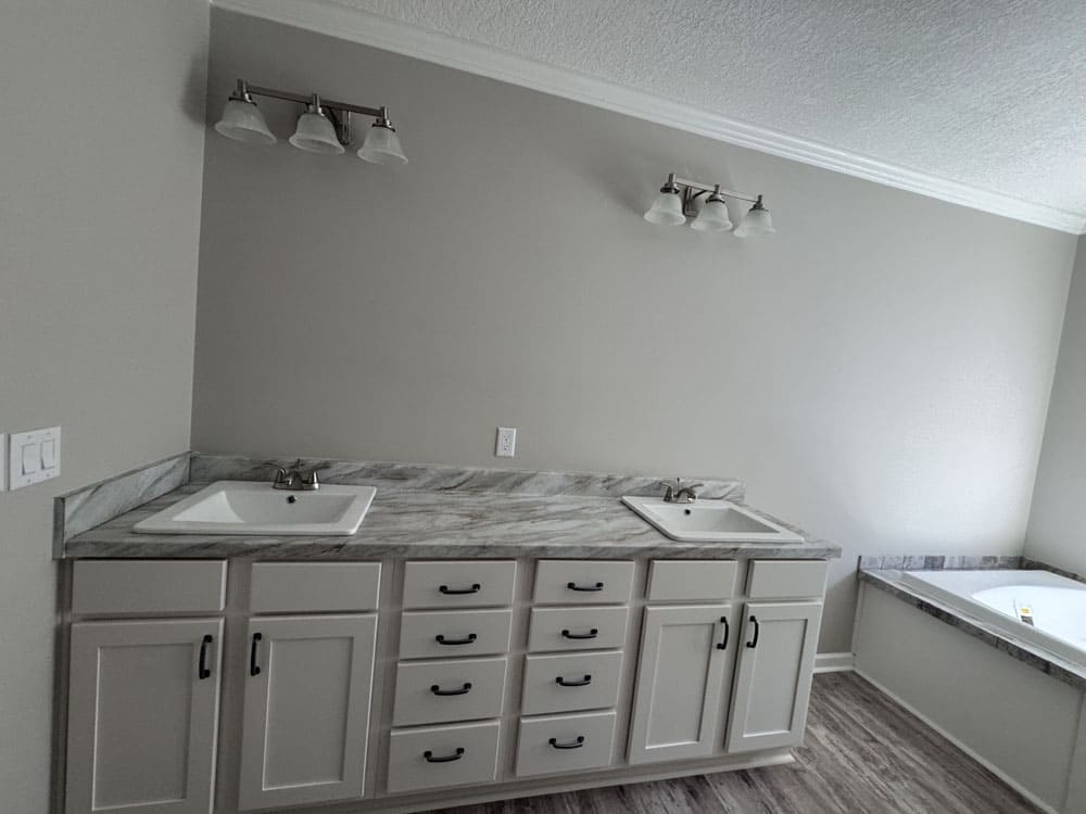 Spacious primary bathroom with double vanity and soaking tub in The Ace manufactured home