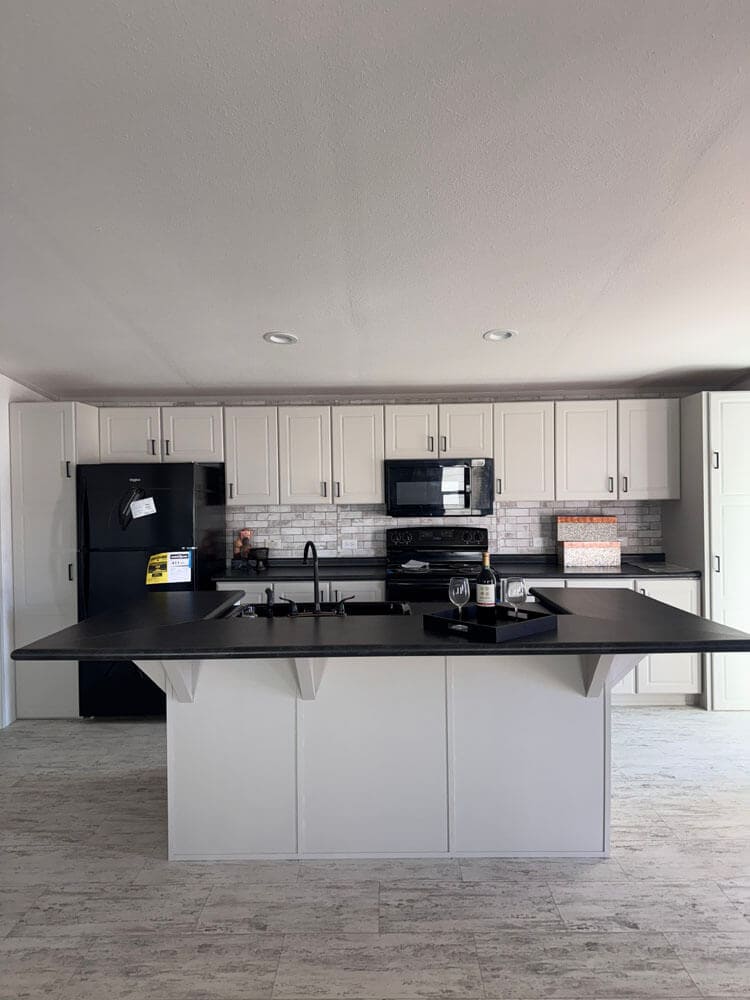 White kitchen cabinets and breakfast island in The Lucia manufactured home