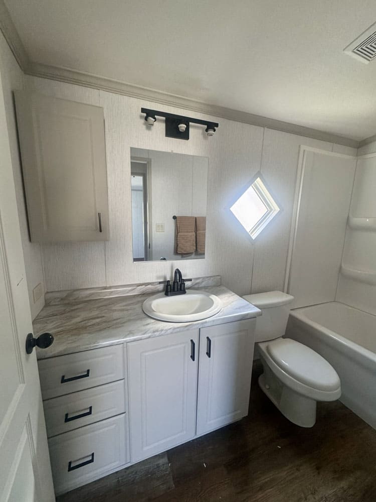 Full bathroom with white vanity and tub in a singlewide home near Conroe