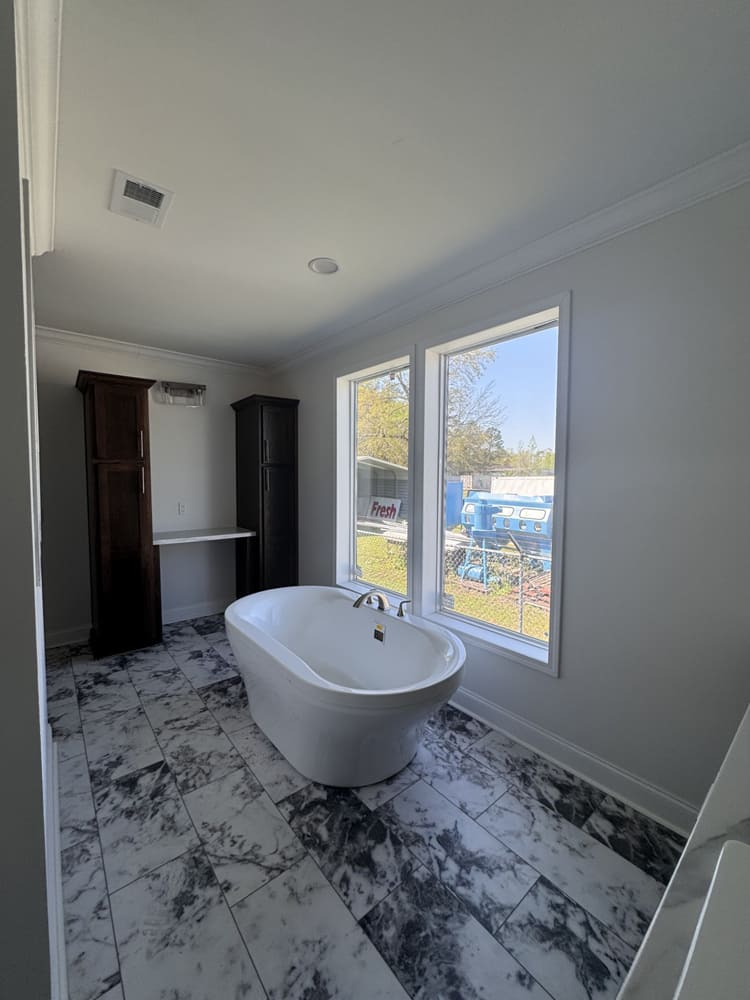 Freestanding soaking tub beneath tall windows in The Shoreline primary bath