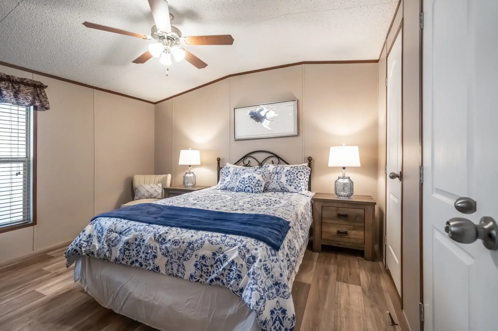 Primary bedroom in The Lisa by Legacy Housing with a vaulted ceiling, ceiling fan, window, and wood-look flooring