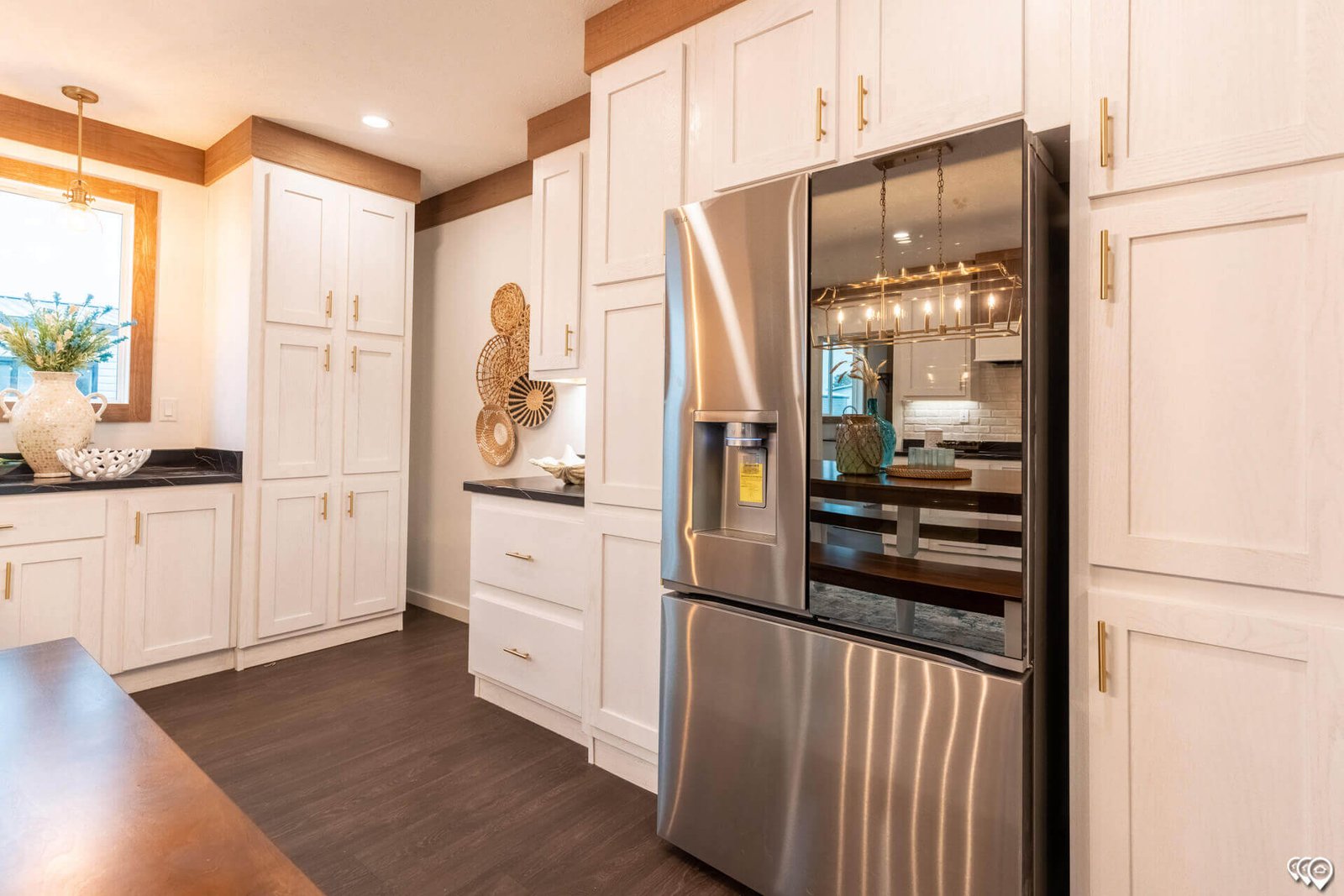 Kitchen refrigerator surrounded by white storage cabinets in The Trinity CS-3242