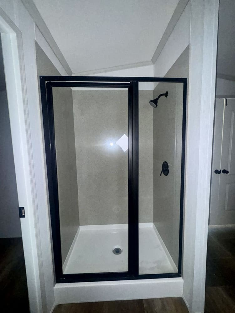 Glass-door shower in the Legacy Housing H-1880-32E primary bathroom