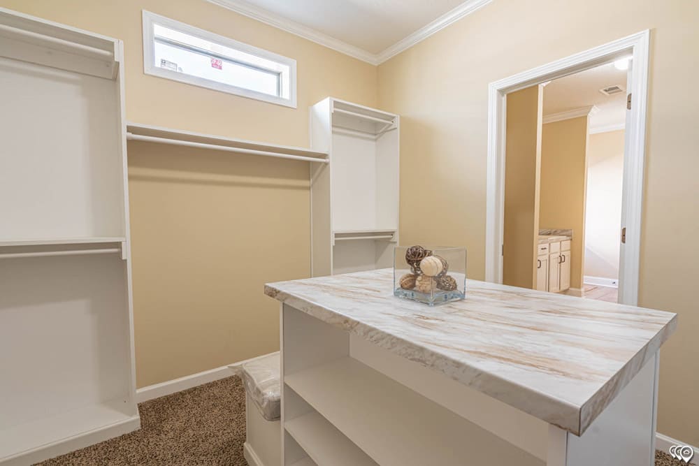Walk-in primary closet with center storage island in this Austin-area modular home