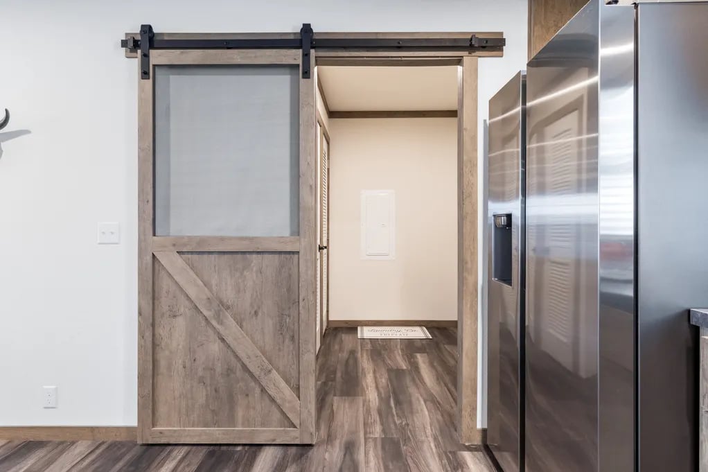 Rustic sliding barn door beside the refrigerator in the Isabella Elite double-wide