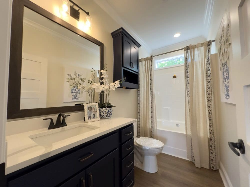 Guest bathroom with tub-shower and navy vanity in The Riverwalk