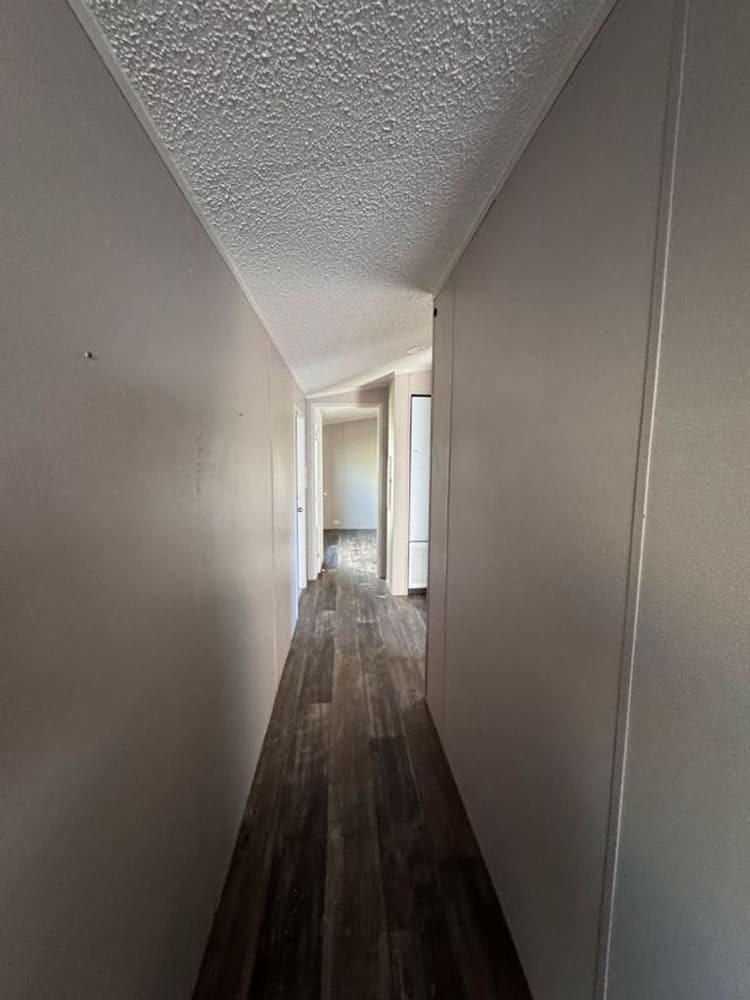 Long interior hallway with wood-look flooring in The Leyla at Premier Homes of Conroe