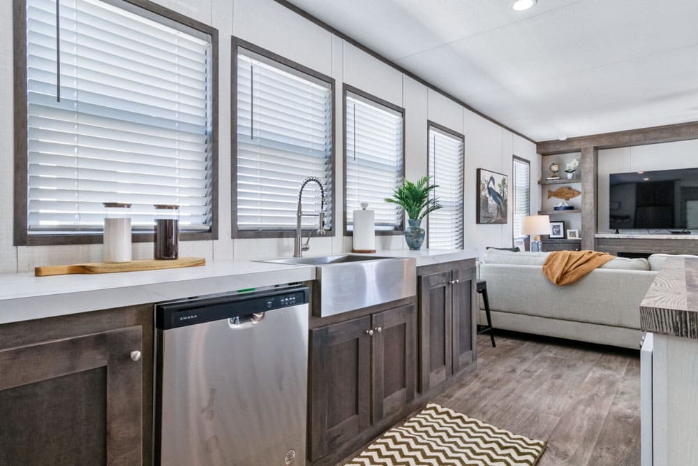 Farmhouse sink, stainless dishwasher and living area in The Wilson manufactured home