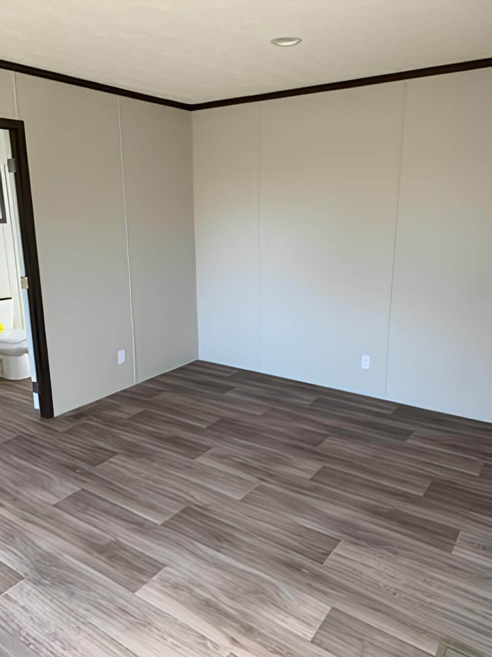 Primary bedroom with wood-look floors and ensuite access in The Spirit