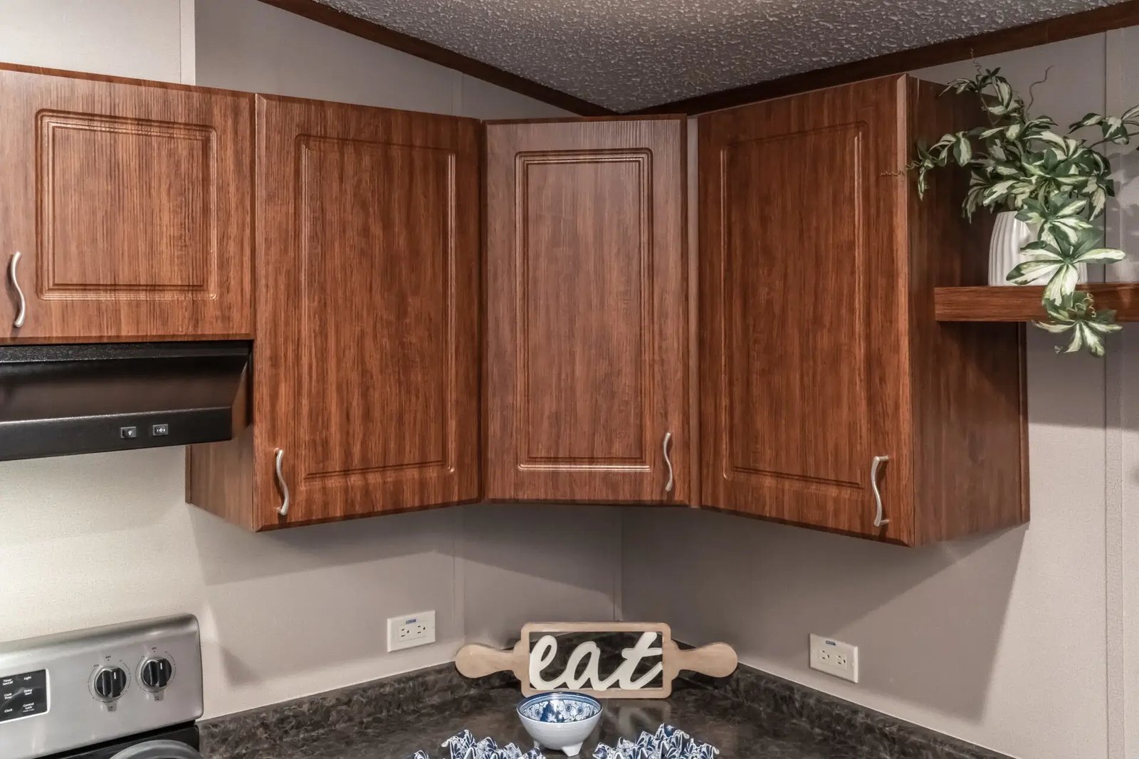 Upper kitchen cabinetry in The Lisa with raised-panel wood-tone doors, curved hardware, and open display shelving