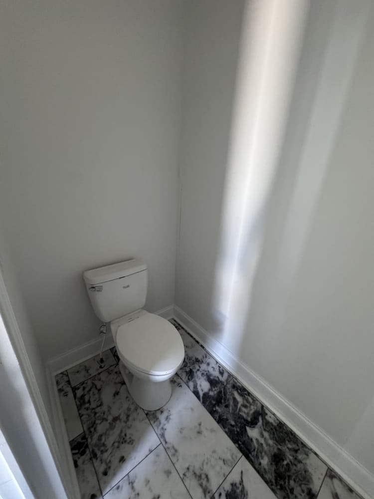 Private toilet room with marble-look flooring in The Shoreline primary bath