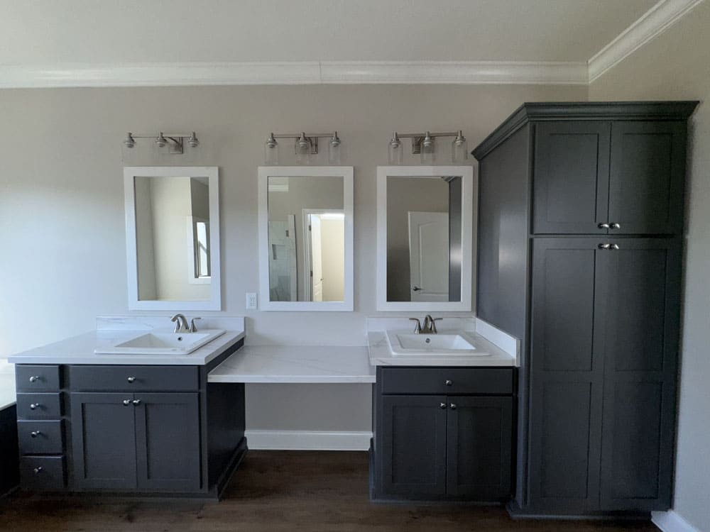 Separate bathroom vanities with makeup counter and tall storage cabinet in this modular home for sale near Conroe