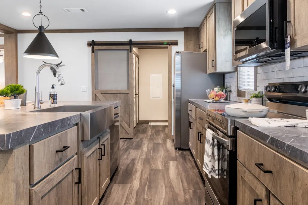 Galley kitchen with farmhouse sink, stainless appliances and barn door in the Isabella Elite