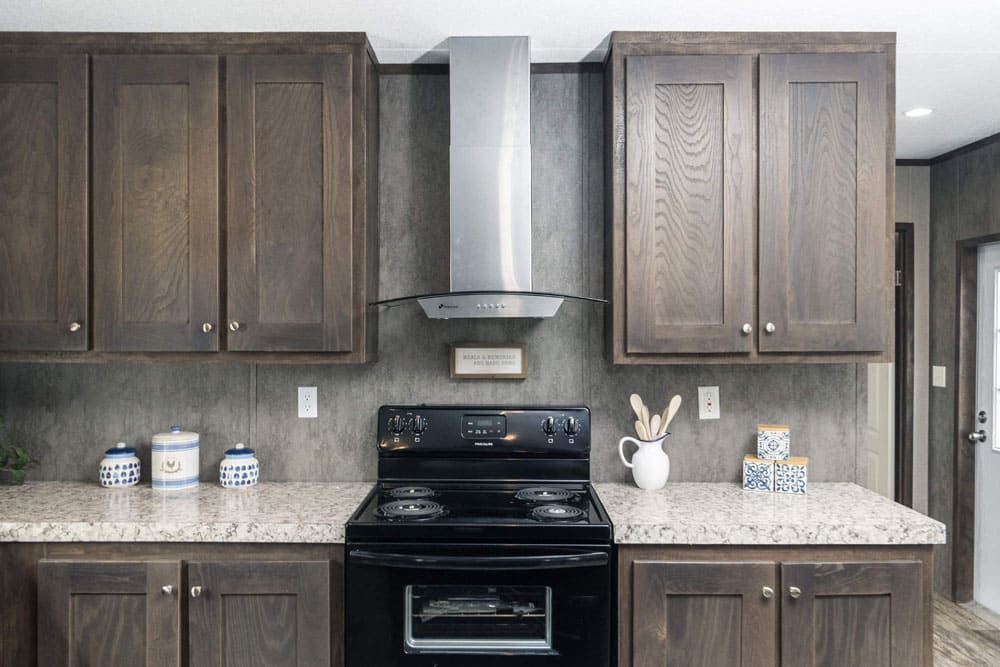 Black range, vent hood, and dark wood cabinets in the Jessup Grant kitchen