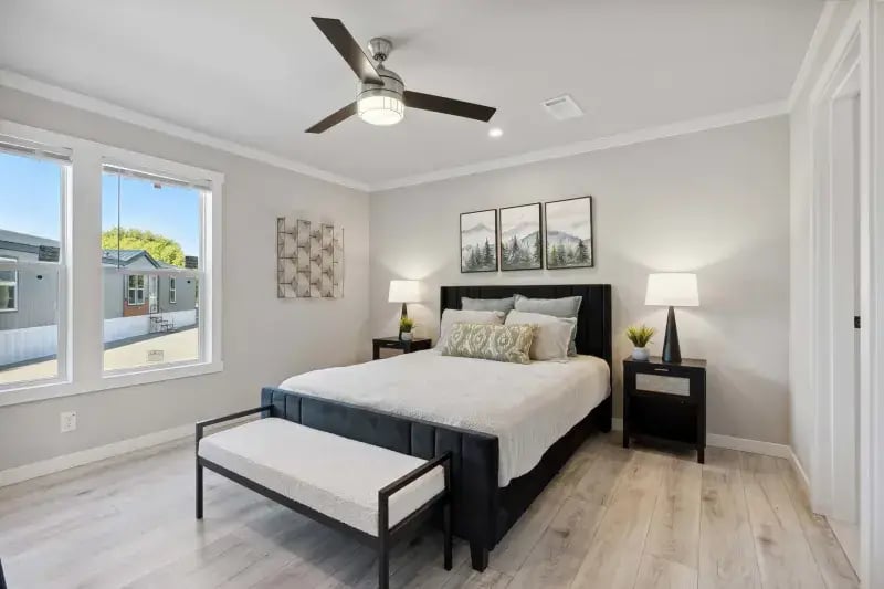 Primary bedroom with large windows and ceiling fan in The Carol 4-bedroom home