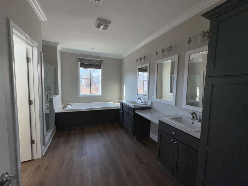 Primary bathroom with soaking tub, glass shower and dual vanities in The Lilly II