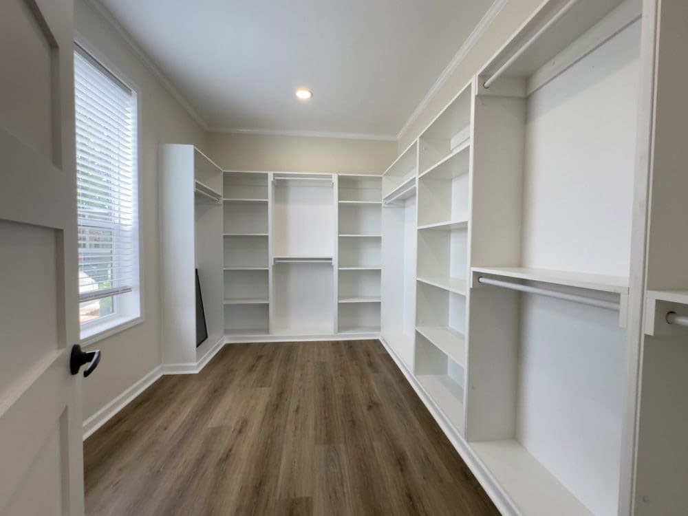 Walk-in primary closet with built-in shelving in The Riverwalk