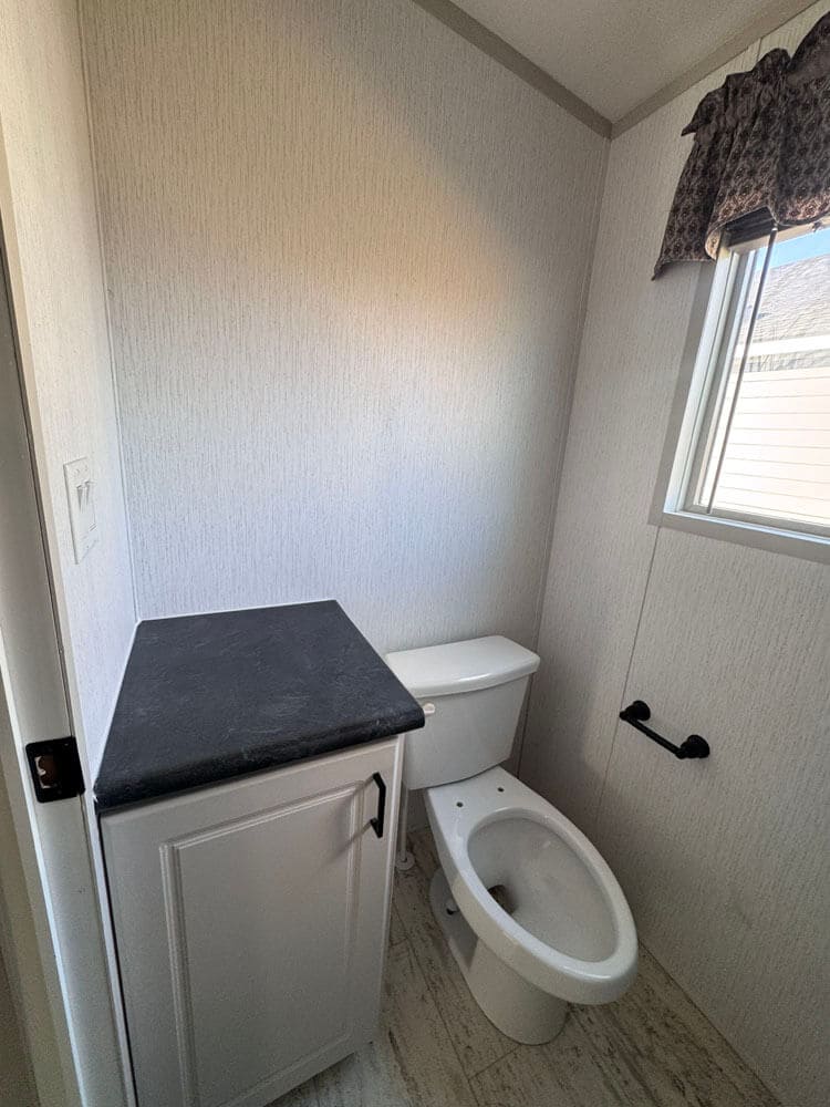 Private toilet room with storage cabinet in The Lucia mobile home