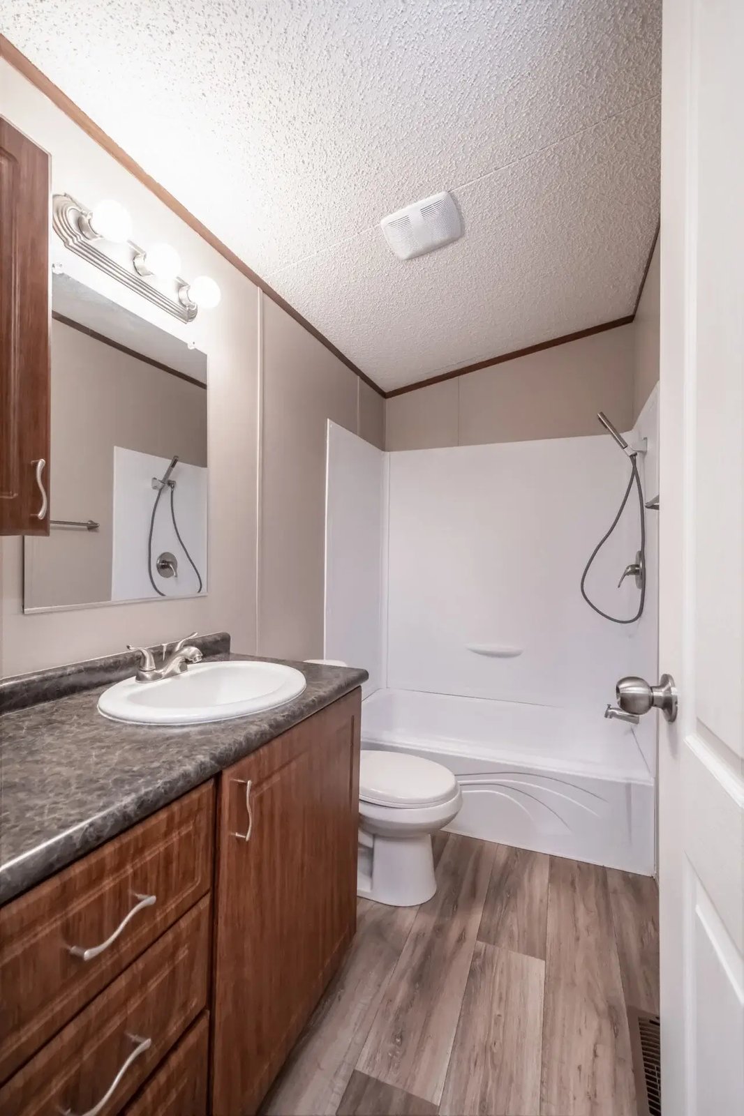 Bathroom in The Lisa with a single vanity, wood cabinet storage, toilet, and tub-and-shower combination