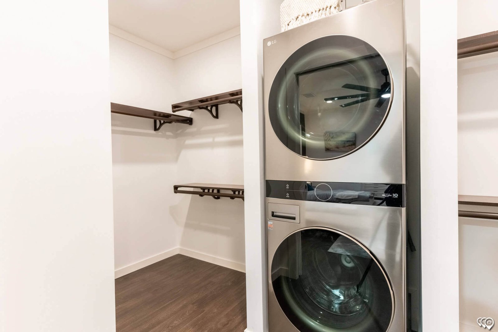 Stacked washer and dryer beside walk-in closet shelving in The Trinity CS-3242