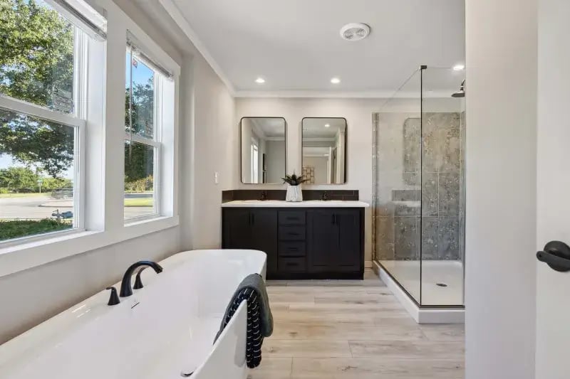 Primary bathroom with freestanding tub, dual vanity and glass shower in The Carol