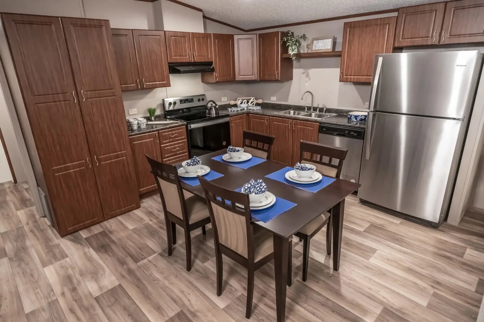 Kitchen and dining area in The Lisa with wood cabinetry, stainless-look appliances, pantry storage, and seating for four